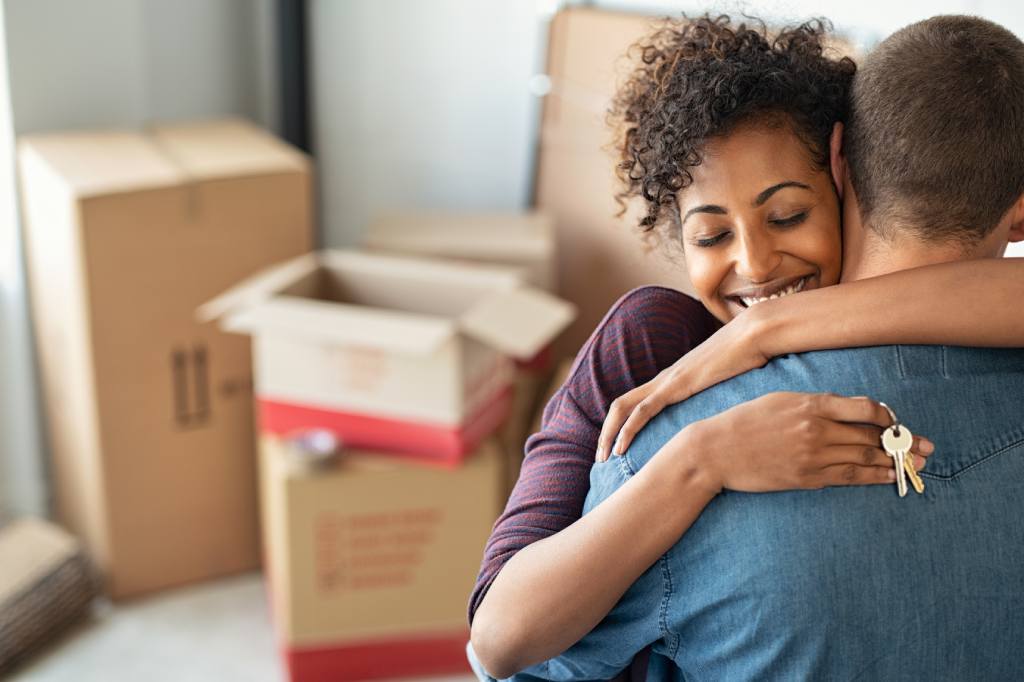 A couple hugging amid boxes in their new home 