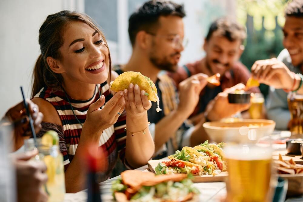 A woman picks up a taco at a restaurant table. 