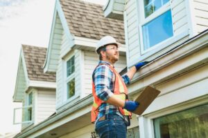 A home inspector on a ladder looking at a roof