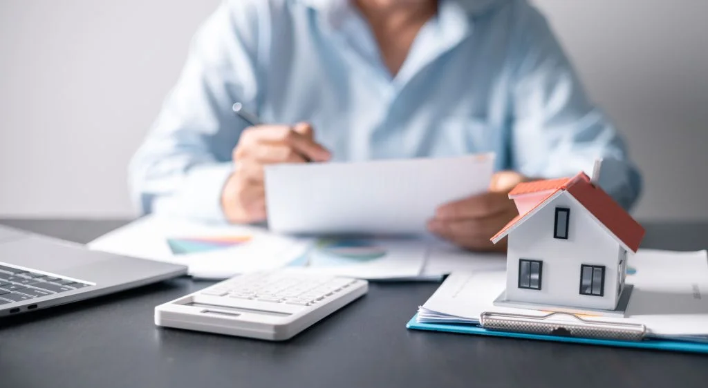 A model home sits on a table as a homeowner reviews their taxes.