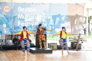 Traditional dancers perform on stage under the Reston Multicultural Festival banner at Reston Town Center