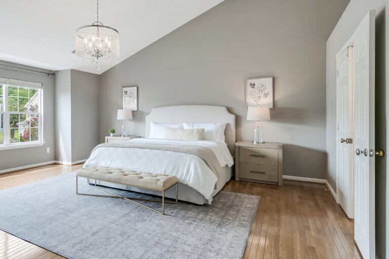 After staging: primary bedroom at 3985 Fawnridge Ct with upholstered bed, matching nightstands and a light rug under the vaulted ceiling