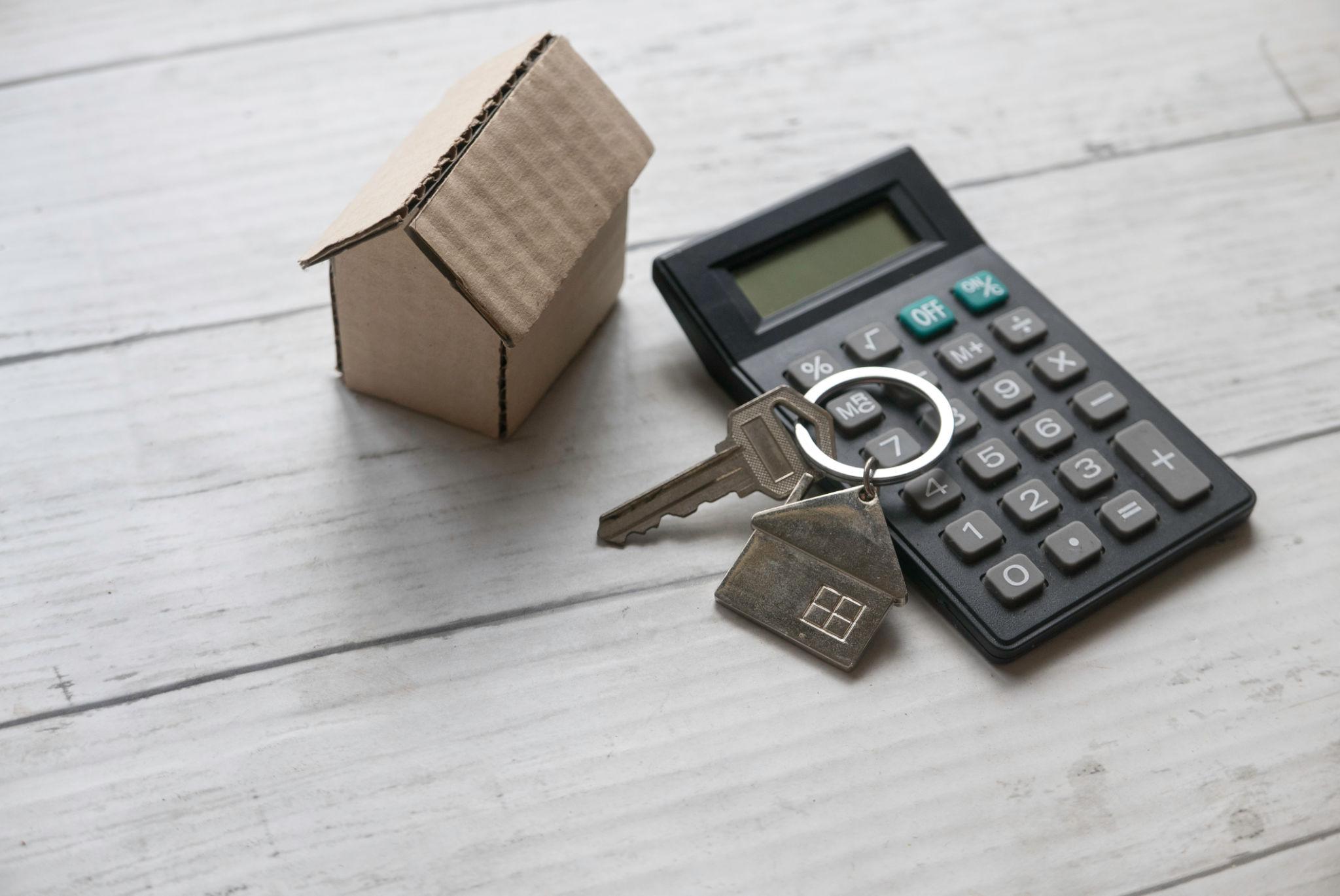 House keys, calculator, and real estate documents arranged on a desk.