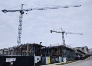 Halley Rise construction site in Reston VA with two tower cranes, scaffolding and a Halley Rise branded construction fence, apartments in the background