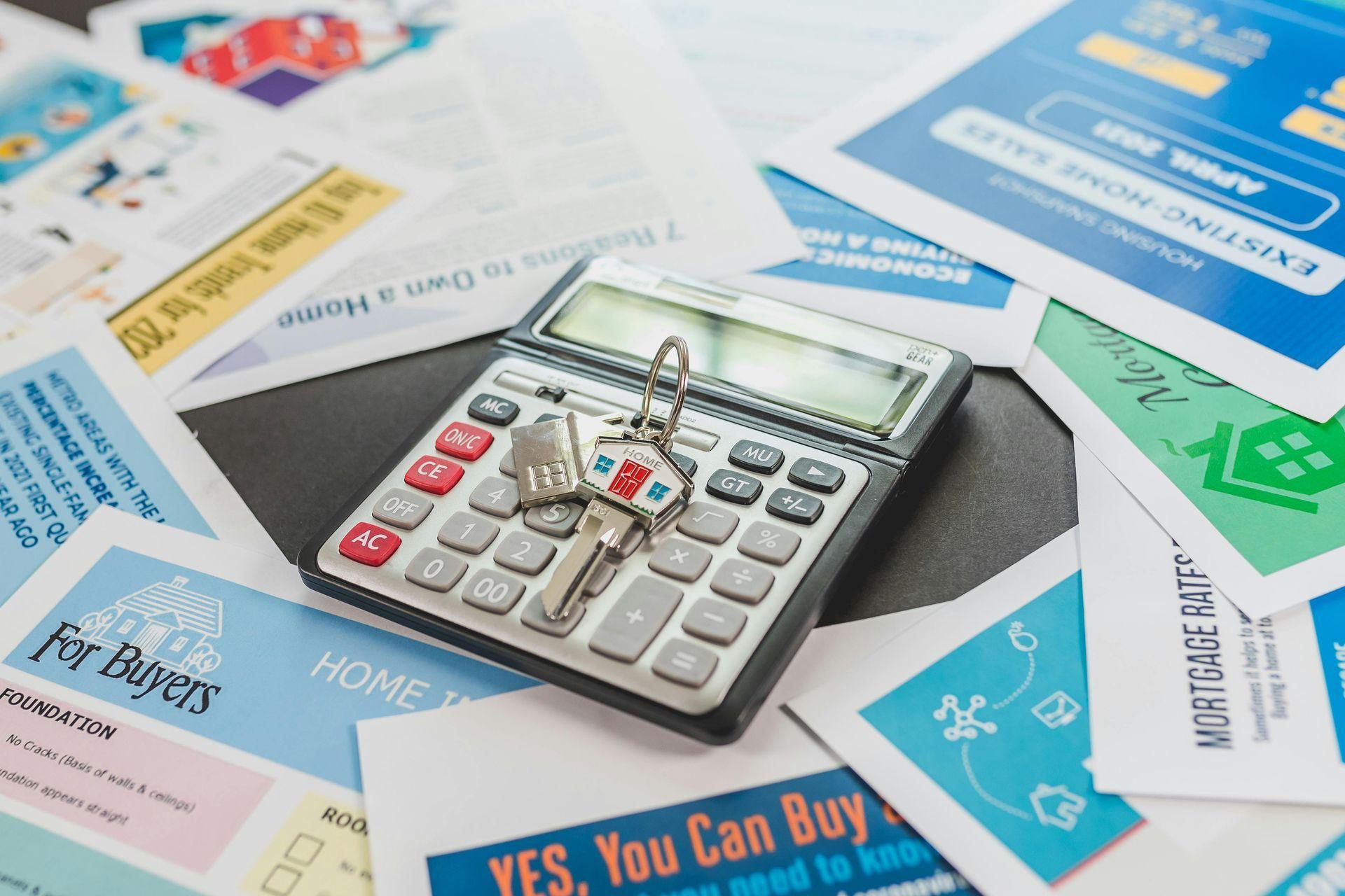 Calculator and homebuying documents arranged on a desk for financial planning.