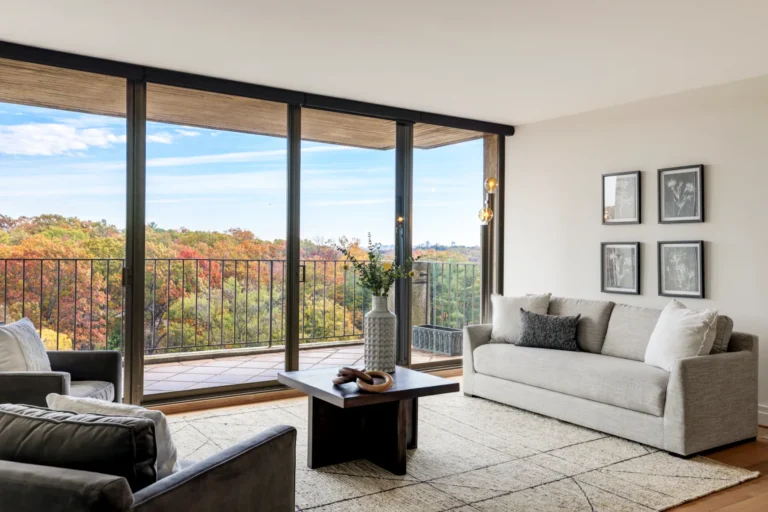 Living room with floor-to-ceiling windows and a fall treetop view