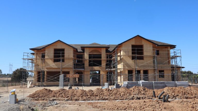 A new two-story house under construction with scaffolding, illustrating custom home building