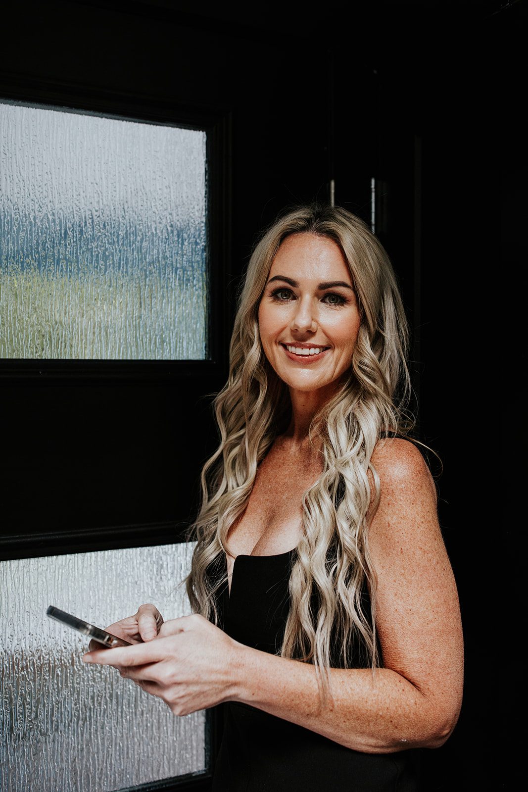 Nikki Lagouros, Northern Virginia realtor, smiling in a kitchen with her phone