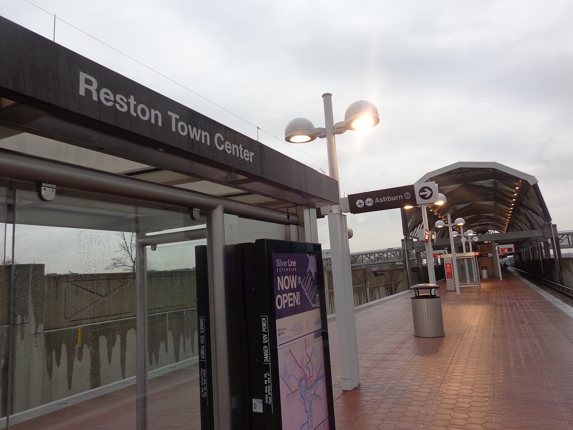 Reston Town Center Metro station platform with the station name sign, a Now Open poster and platform lights on an overcast day